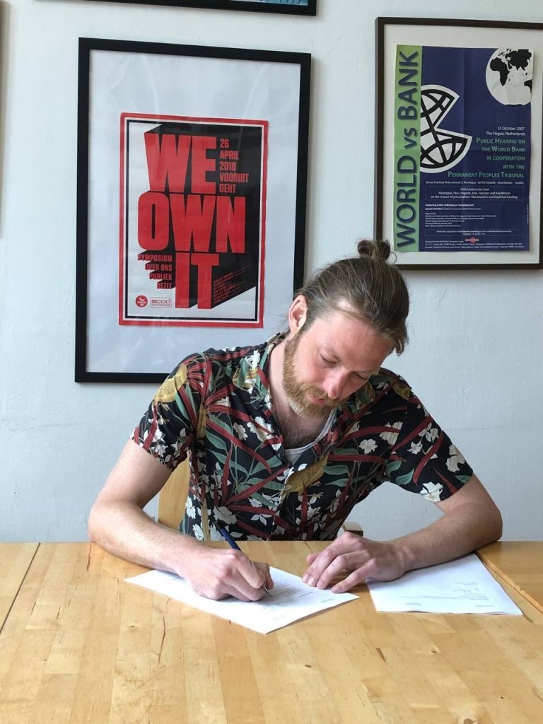 A member signing papers in front of a 'We own it' poster