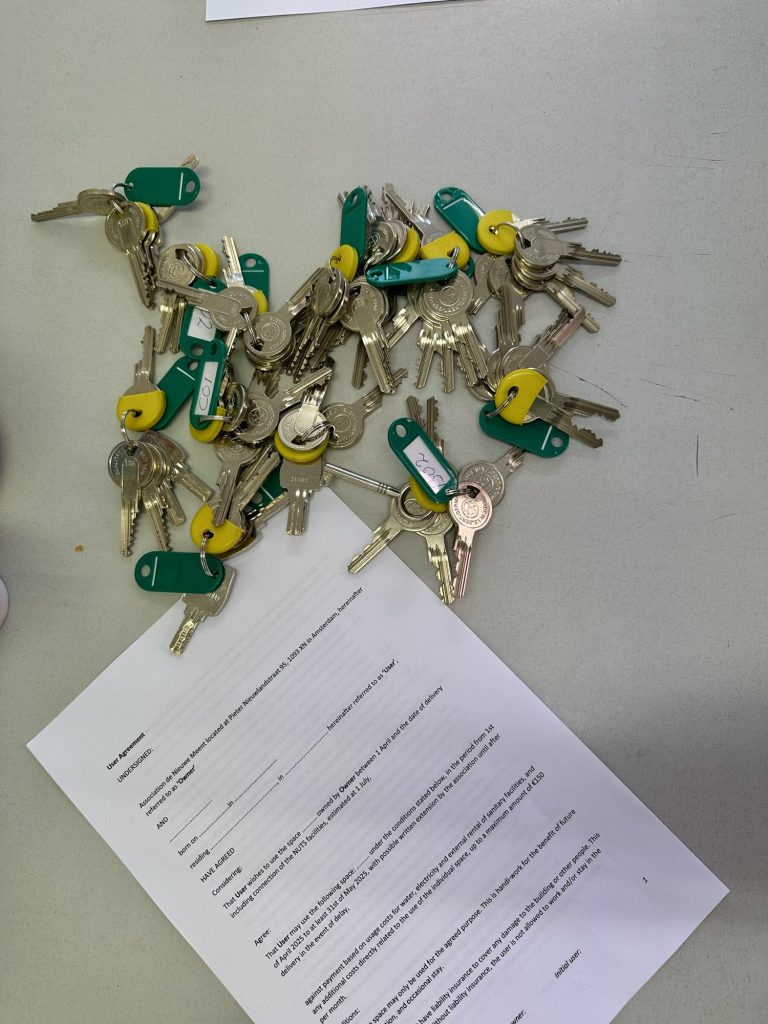 A pile of keys with green tags on top of a handover document